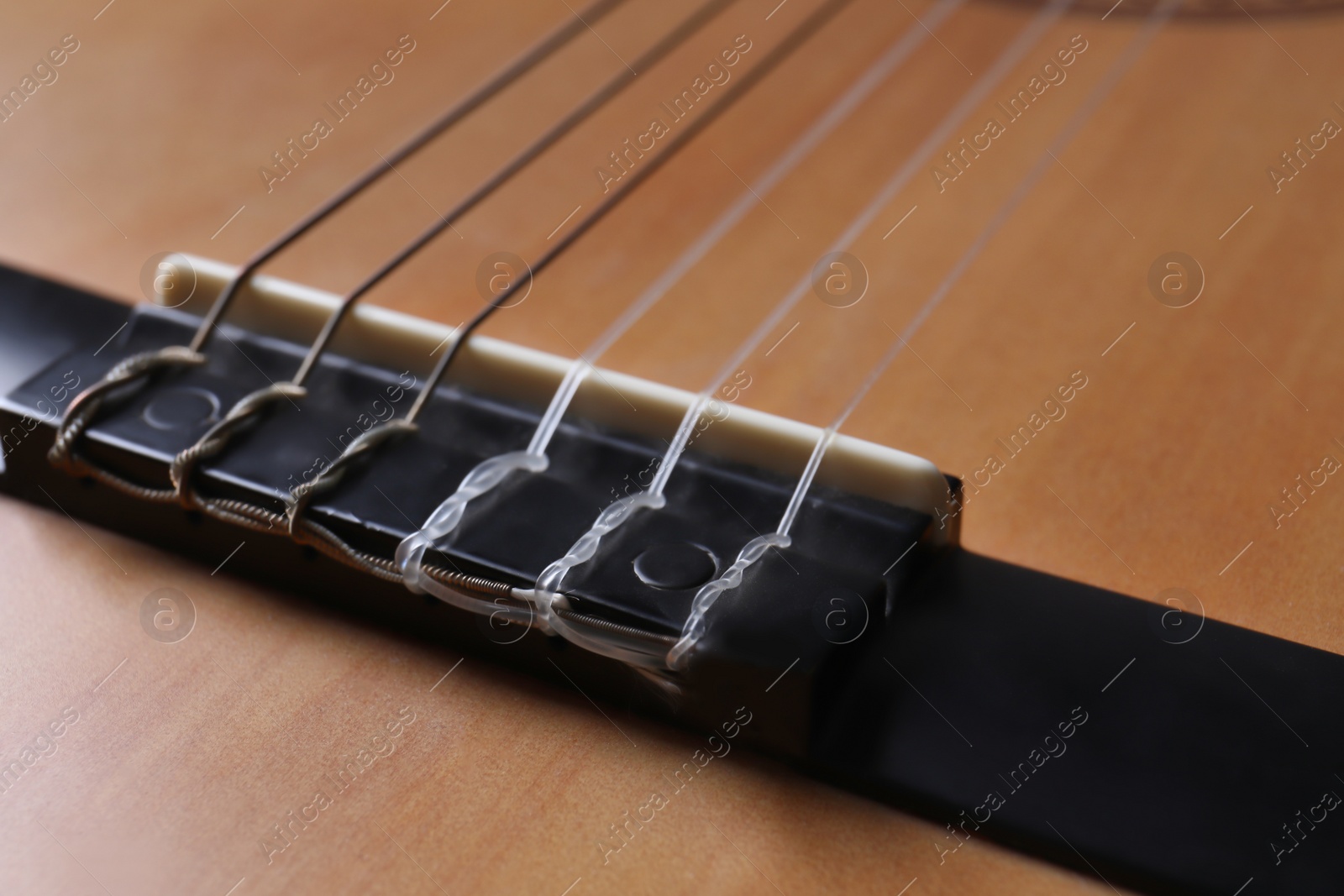 Photo of Closeup view of acoustic guitar, focus on bridge with strings
