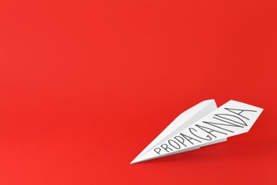Photo of Paper plane with word Propaganda on red background, space for text