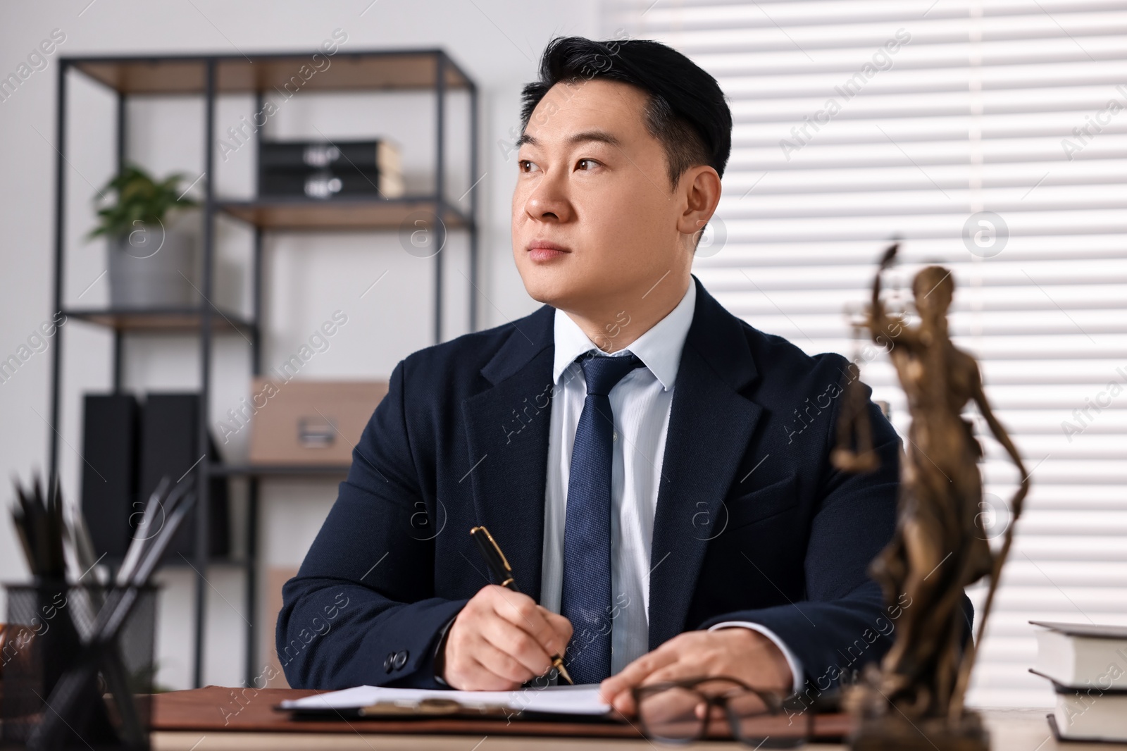 Photo of Notary writing notes at wooden table in office