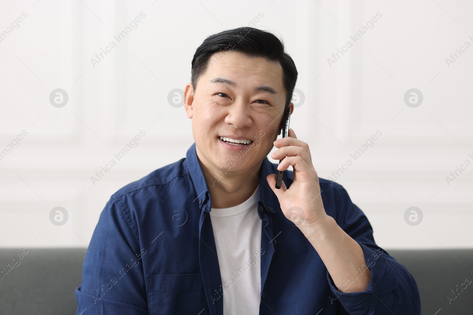 Photo of Portrait of smiling businessman talking by smartphone indoors