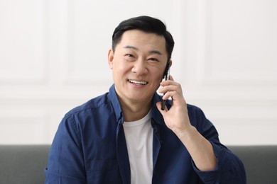Portrait of smiling businessman talking by smartphone indoors