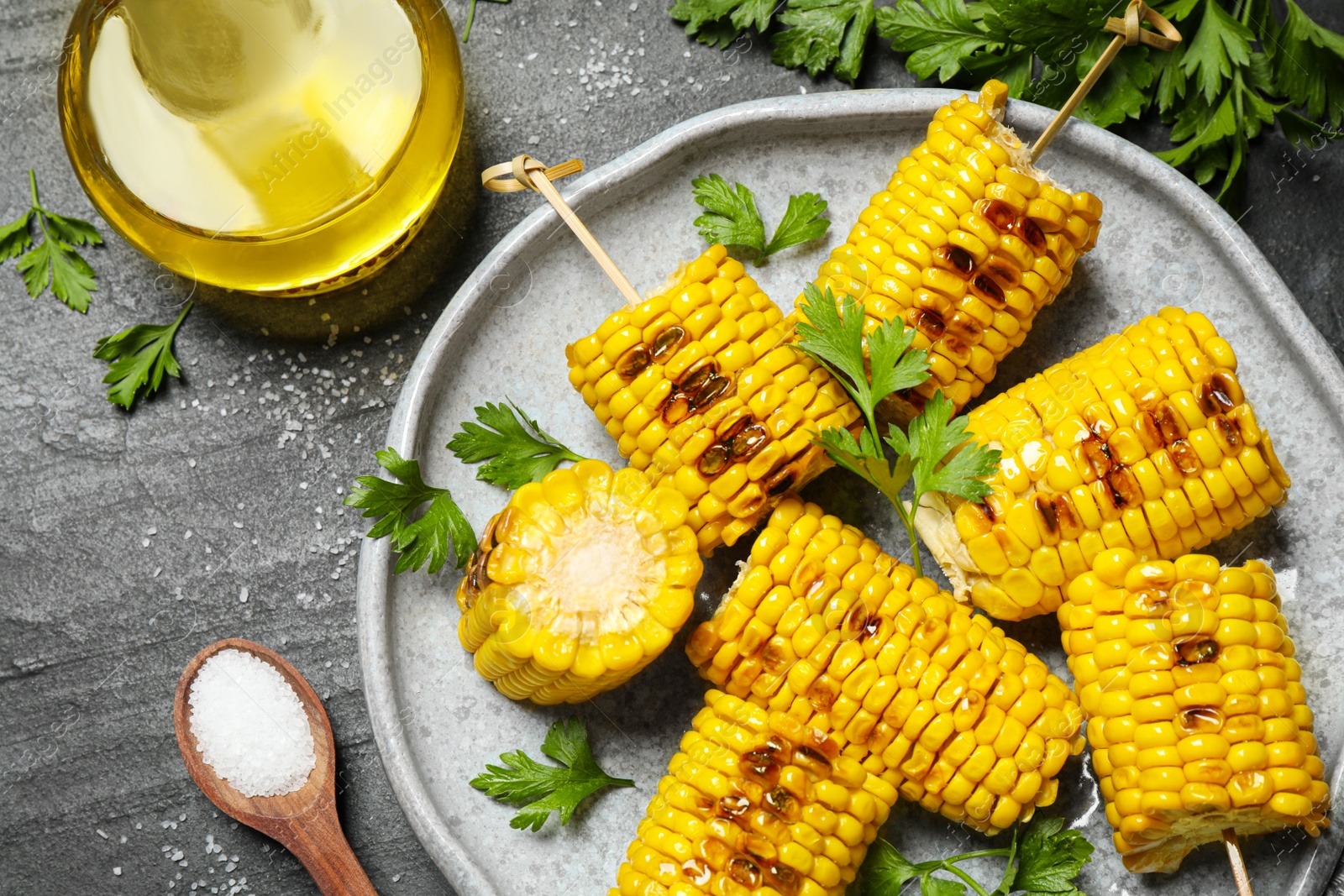 Photo of Delicious grilled corn cobs on grey table, flat lay