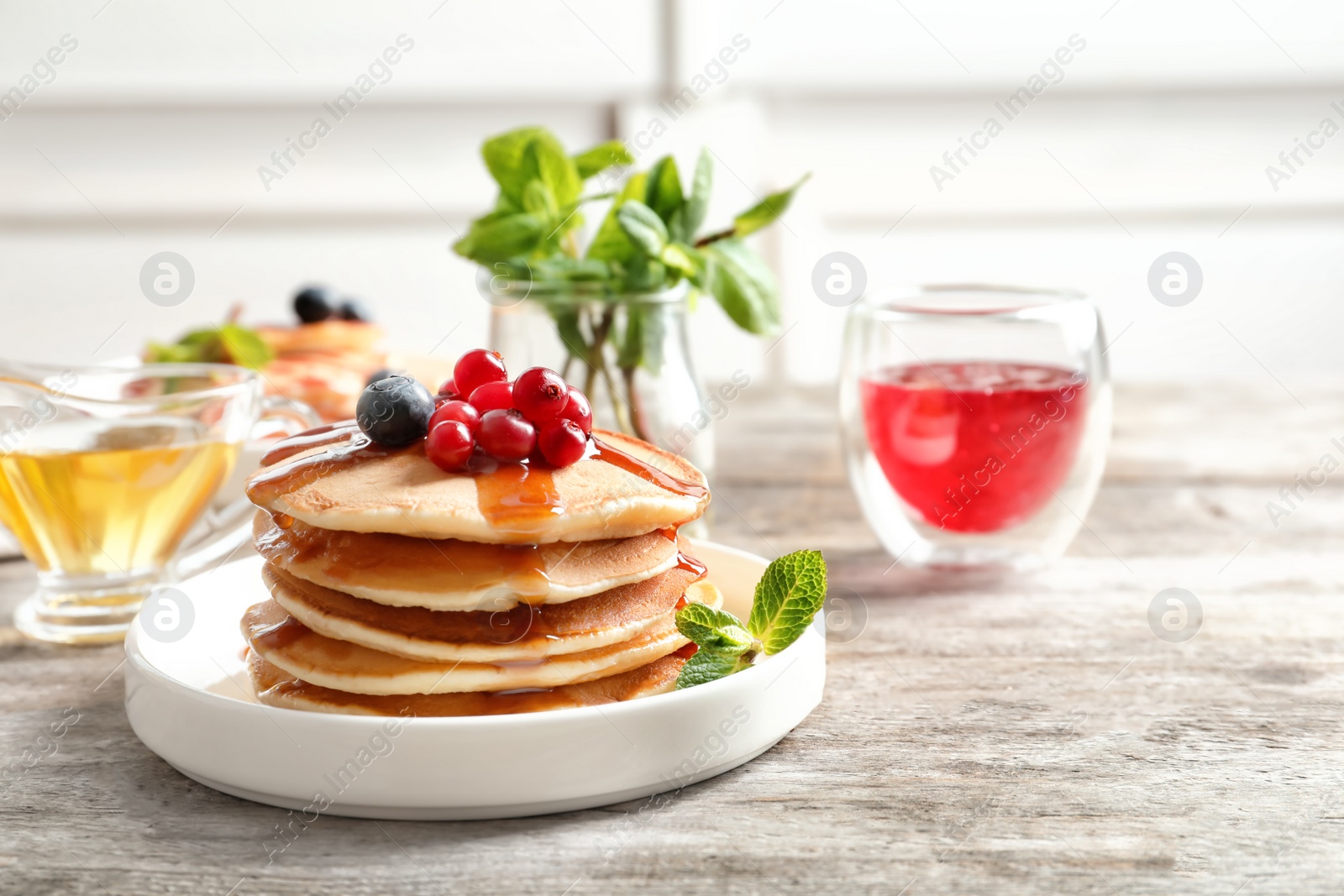 Photo of Stack of tasty pancakes with berries and syrup on table