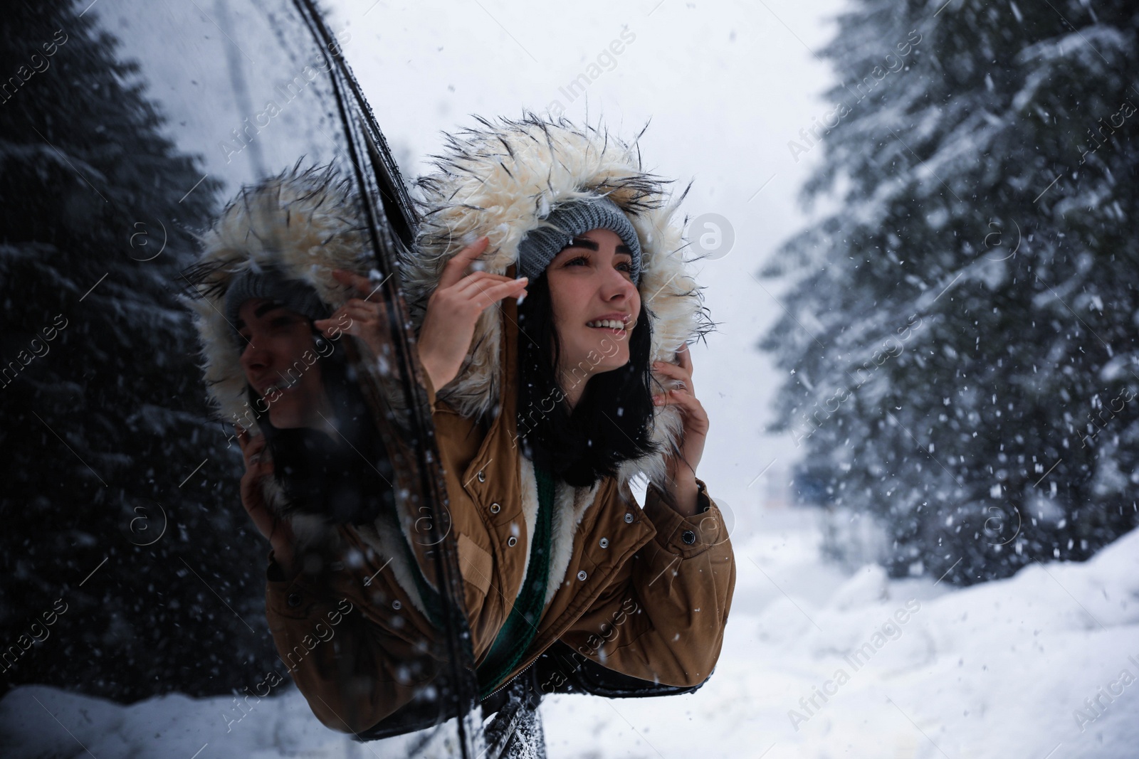 Photo of Young woman looking out of car window on snowy day