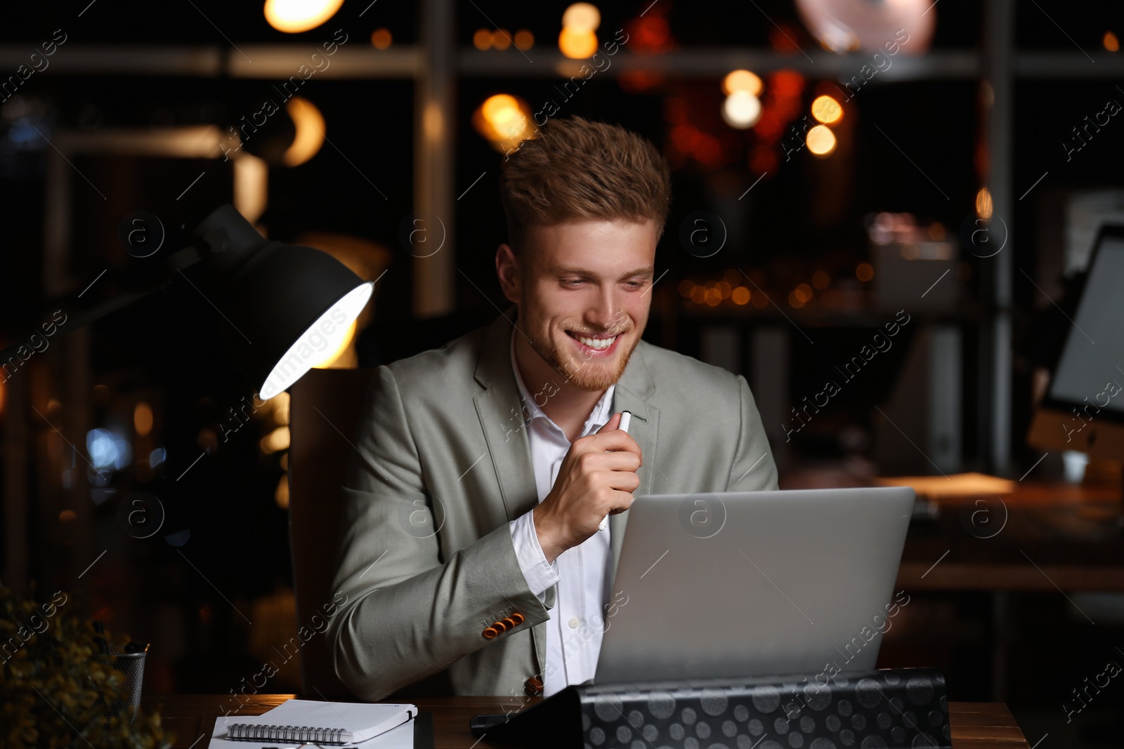 Photo of Young man working in office at night