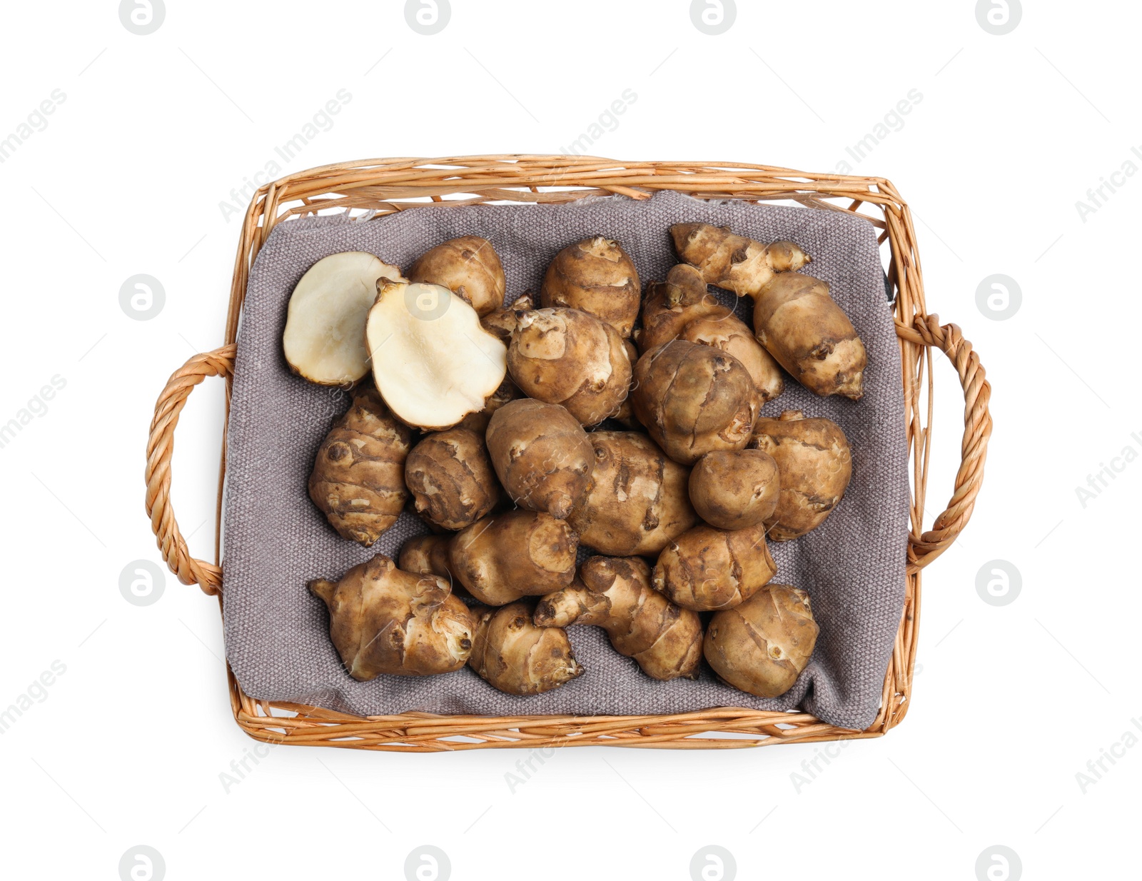 Photo of Wicker basket with many Jerusalem artichokes isolated on white, top view