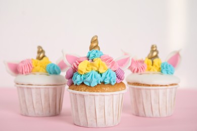 Photo of Three cute sweet unicorn cupcakes on pink table