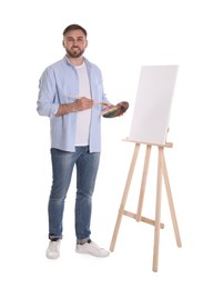 Man with painting tools near easel on white background. Young artist