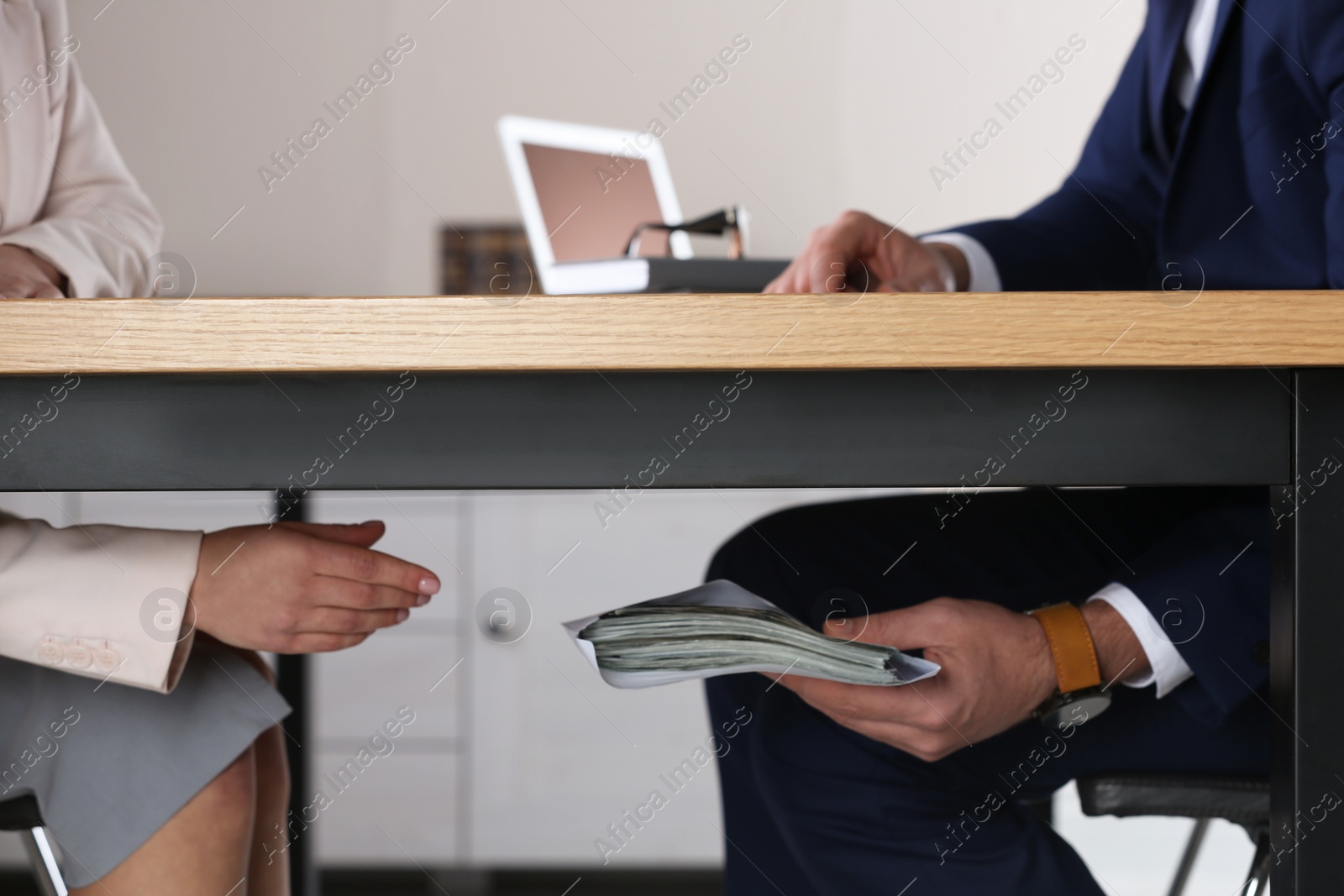 Photo of Man giving bribe to woman under table in office, closeup