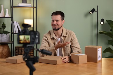 Smiling blogger with many parcels recording video at home