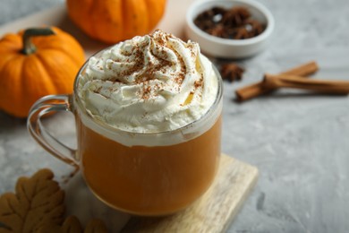 Photo of Cup of pumpkin spice latte with whipped cream on light grey table, closeup