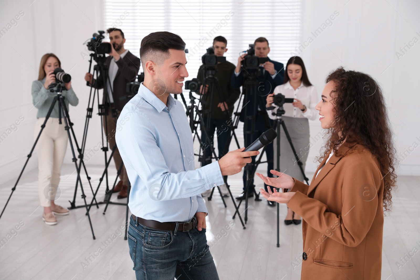 Photo of Professional journalist interviewing young African American woman indoors