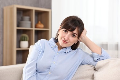 Photo of Portrait of beautiful young housewife on sofa at home