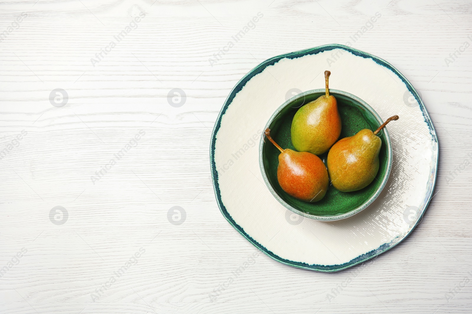 Photo of Dishware with pears on wooden background, top view. Space for text