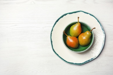 Dishware with pears on wooden background, top view. Space for text