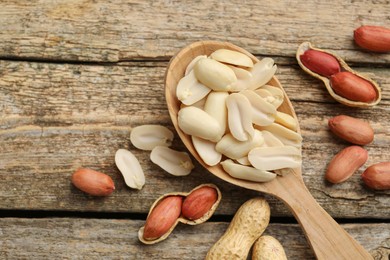 Photo of Fresh peanuts and spoon on wooden table, top view