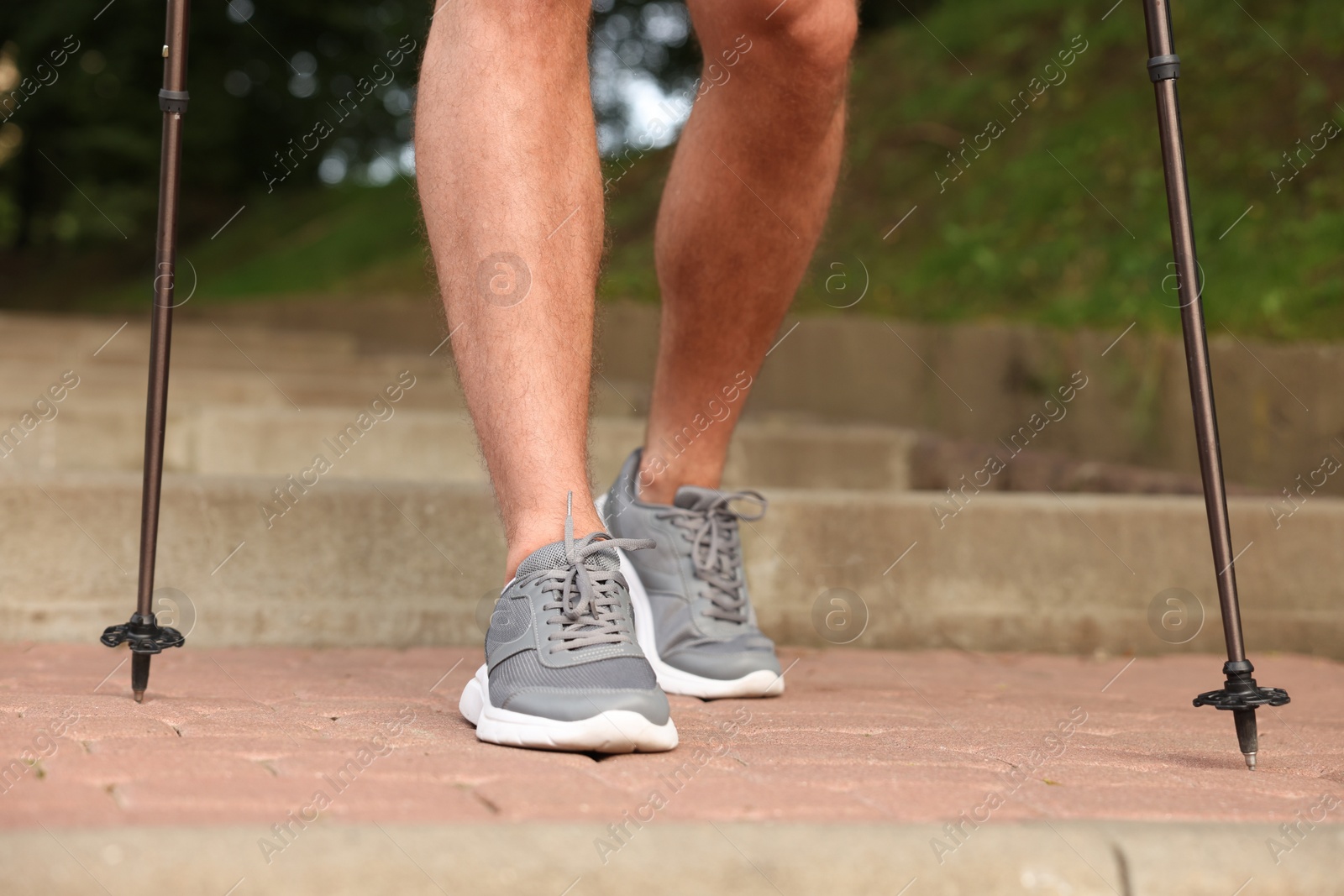 Photo of Man practicing Nordic walking with poles on steps outdoors, closeup