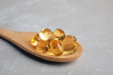 Photo of Spoon with cod liver oil pills on table, closeup