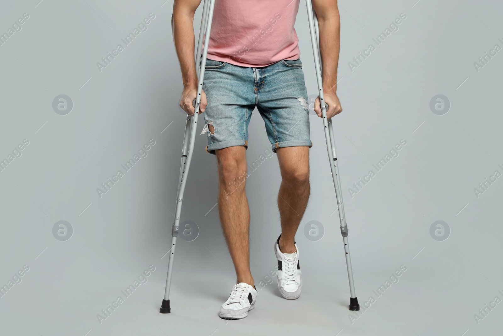 Photo of Man with crutches on grey background, closeup