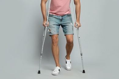 Photo of Man with crutches on grey background, closeup