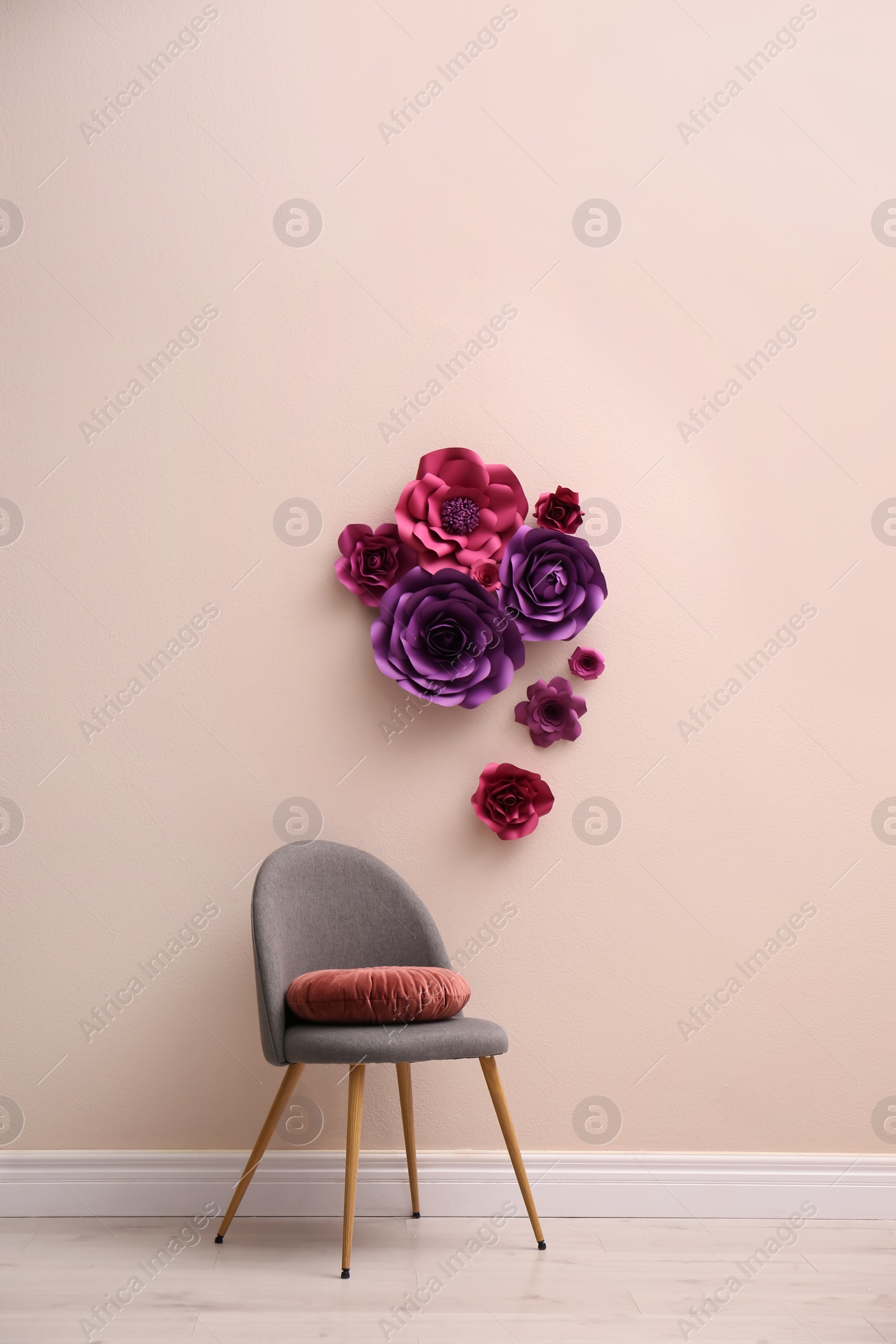 Photo of Chair near wall with floral decor in room. Interior design