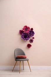 Chair near wall with floral decor in room. Interior design