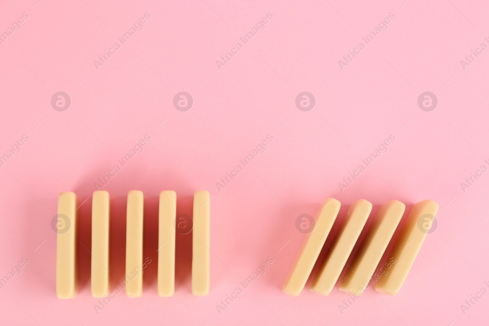 Photo of White domino tiles on pink background, flat lay. Space for text