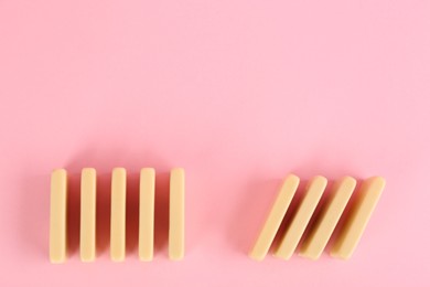 Photo of White domino tiles on pink background, flat lay. Space for text