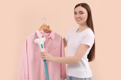 Woman steaming shirt on hanger against beige background