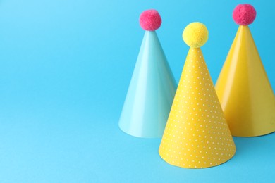 Photo of Colorful party hats on light blue background, space for text