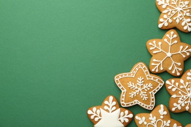 Photo of Tasty Christmas cookies with icing on green background, flat lay. Space for text