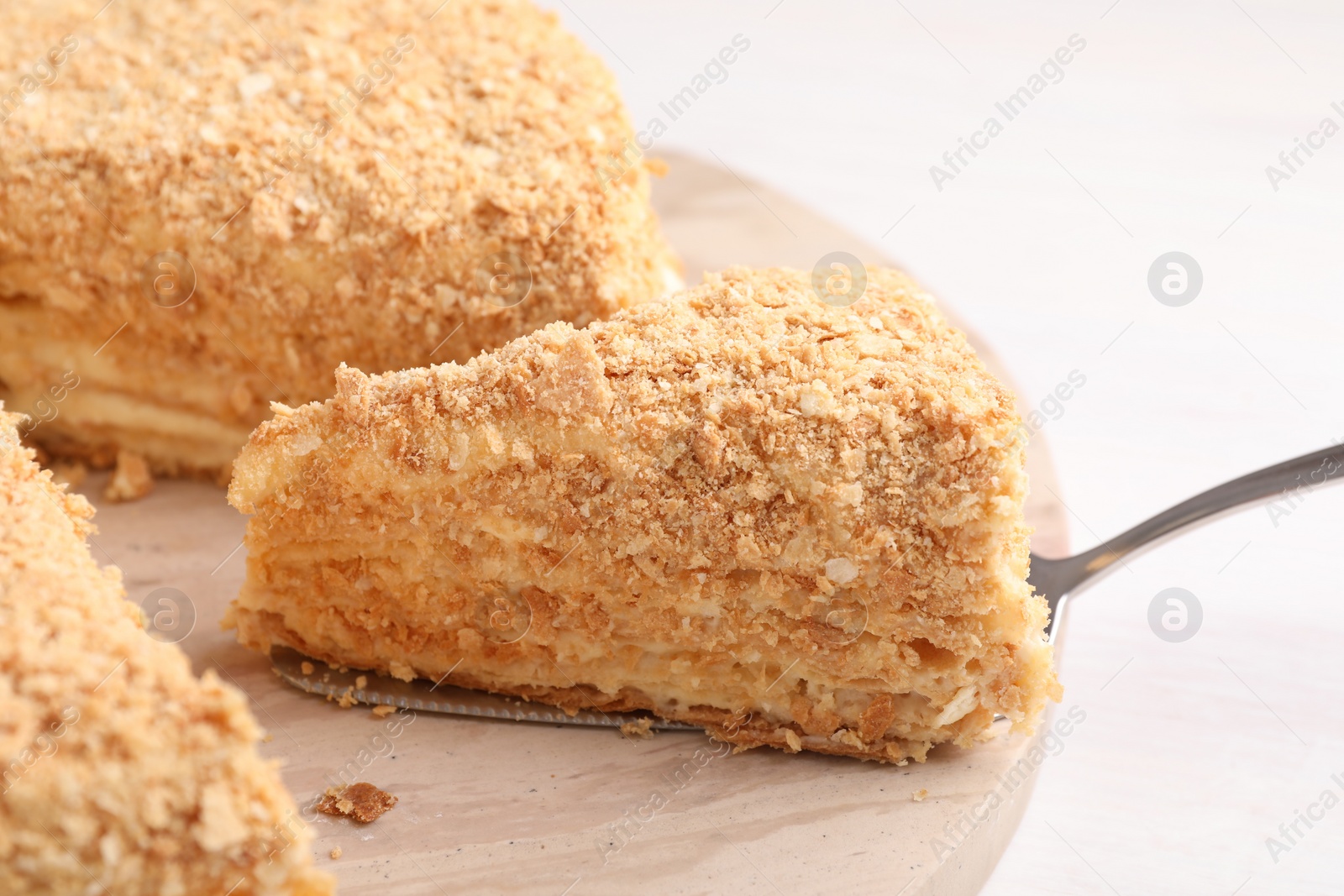 Photo of Taking piece of delicious Napoleon cake from table, closeup