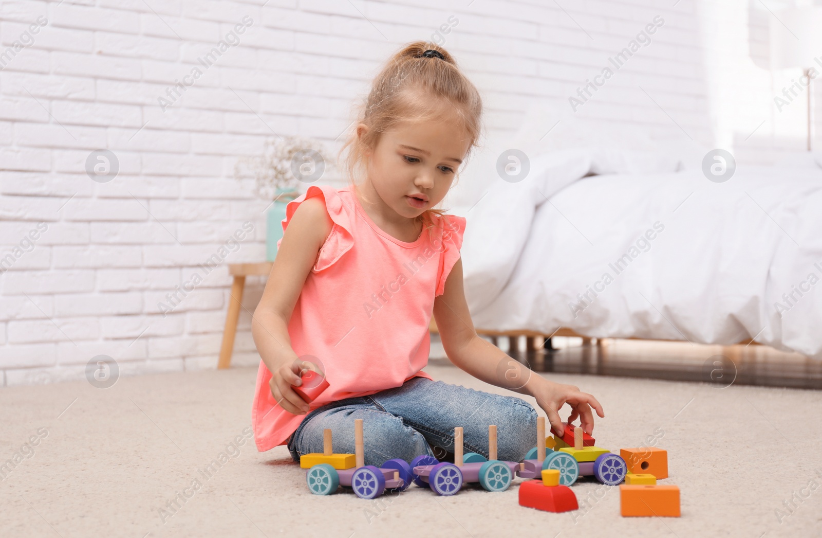 Photo of Cute child playing with wooden train on floor at home