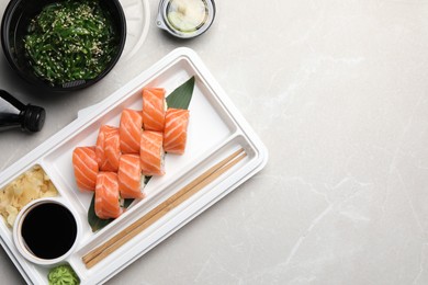 Photo of Delicious sushi rolls served on light grey marble table, flat lay with space for text. Food delivery
