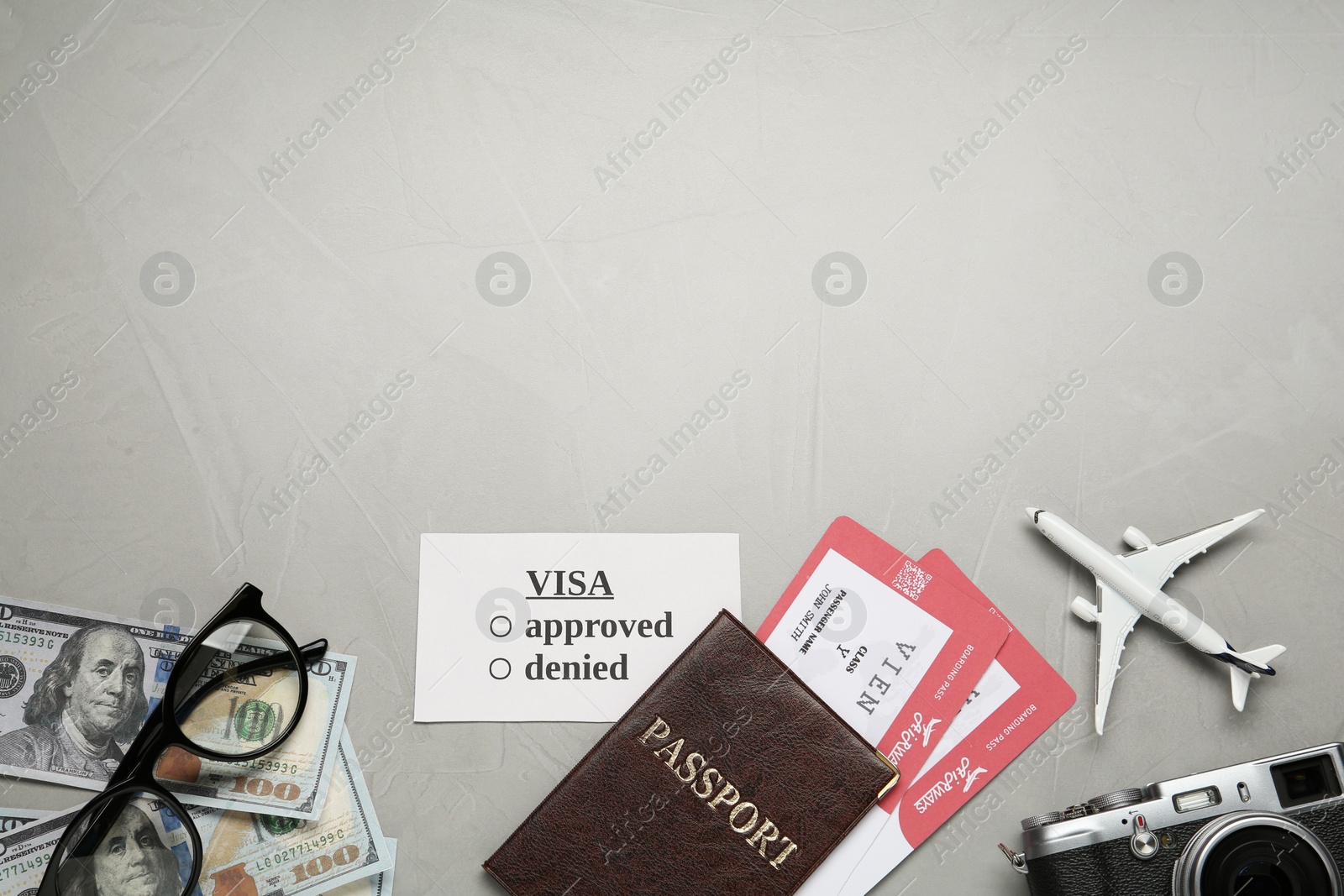 Photo of Flat lay composition with passport, toy plane and camera on grey background, space for text. Visa receiving