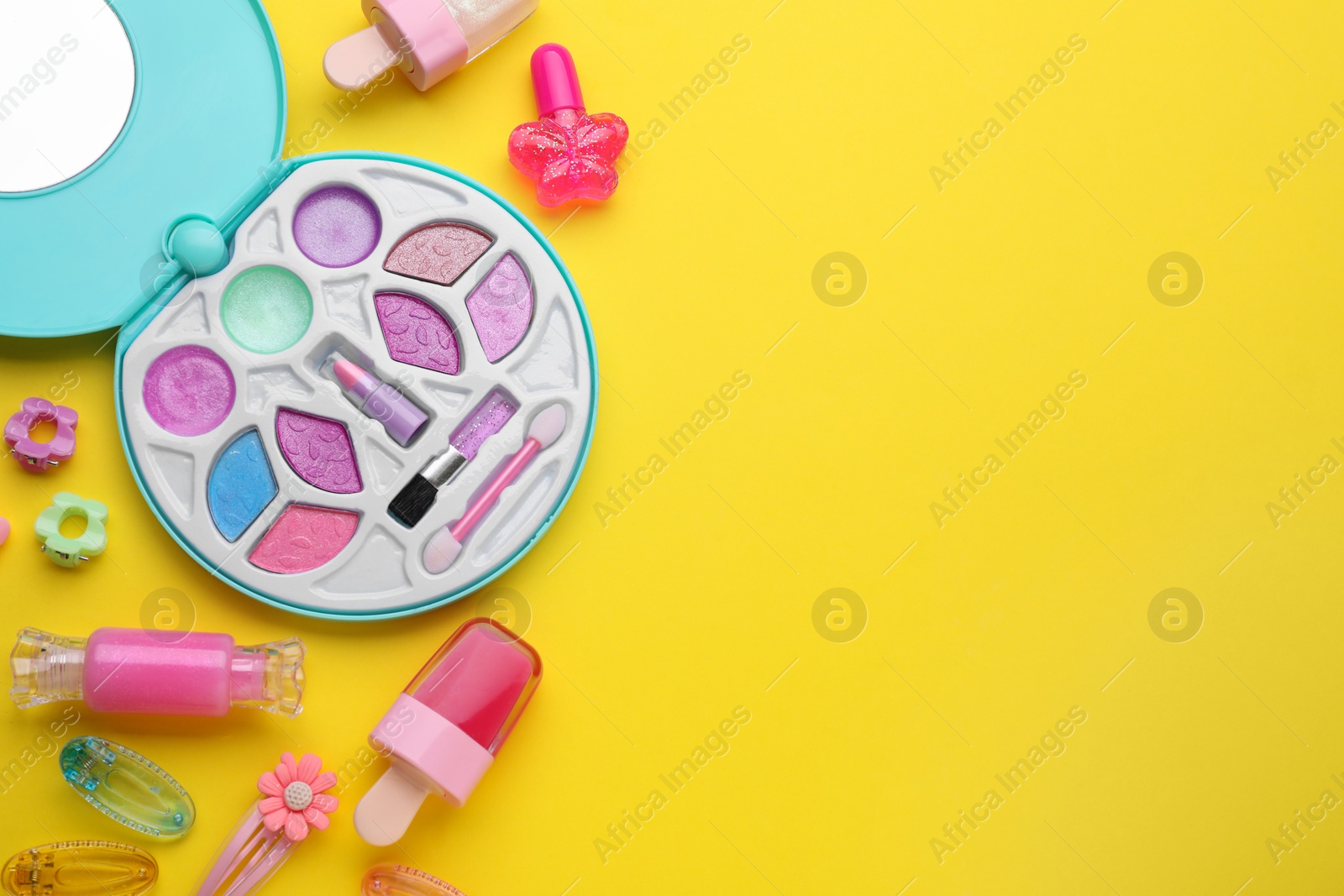 Photo of Eye shadow palette and other decorative cosmetics for kids on yellow background, flat lay. Space for text