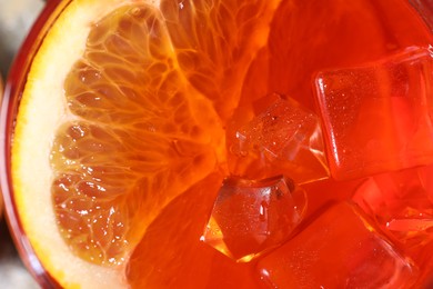 Photo of Aperol spritz cocktail, ice cubes and orange slice in glass, closeup