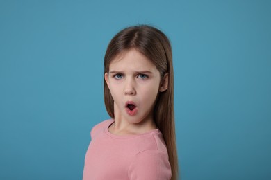Portrait of surprised girl on light blue background