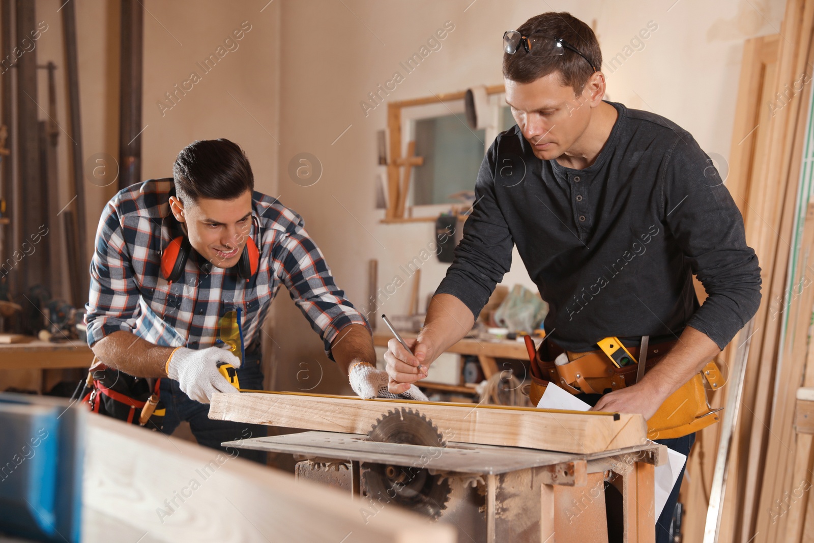 Photo of Professional carpenters working with sawmill machine in workshop