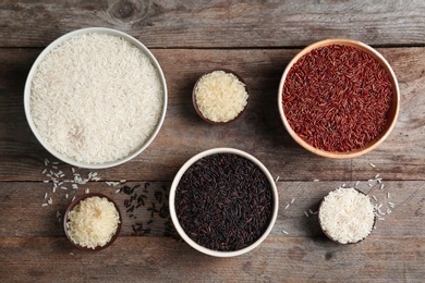 Flat lay composition with brown and other types of rice in bowls on wooden background