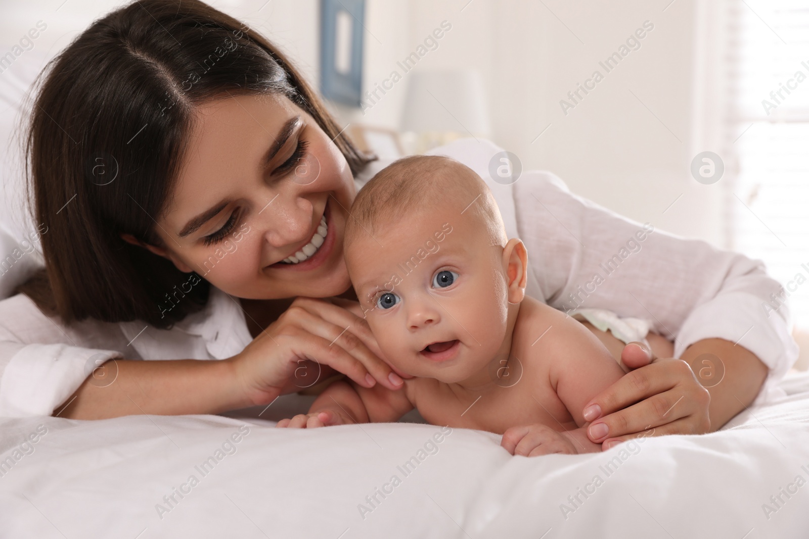 Photo of Happy young mother with her cute baby on bed at home