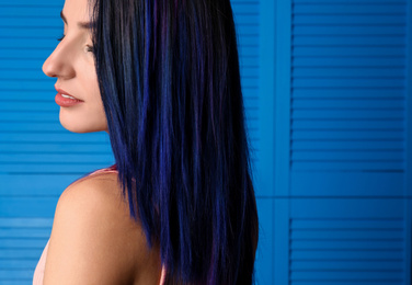 Photo of Young woman with bright dyed hair on blue wooden background