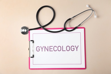 Clipboard with word Gynecology and stethoscope on color background, flat lay