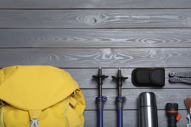 Photo of Flat lay composition with trekking poles and other hiking equipment on grey wooden background, space for text