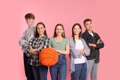 Group of happy teenagers with soft basketball ball on pink background