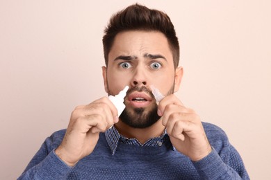 Photo of Man using nasal sprays on beige background
