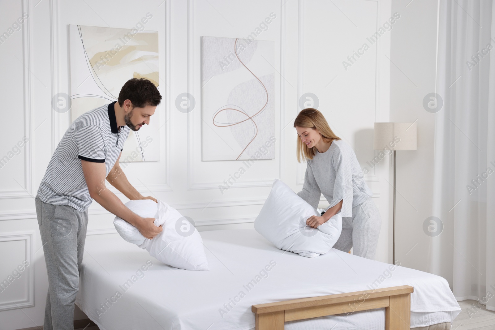 Photo of Couple changing bed linens at home. Domestic chores