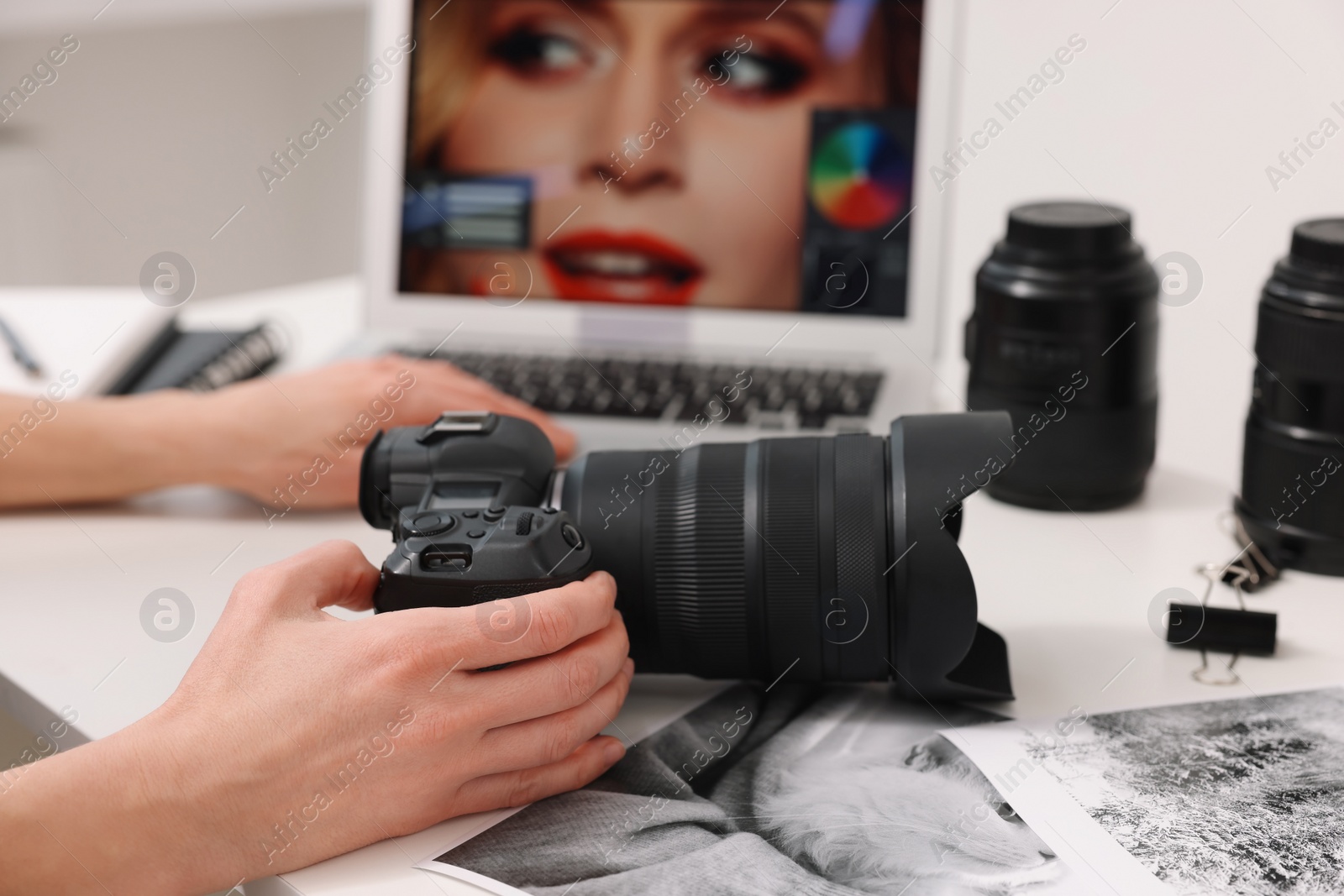 Photo of Professional photographer with digital camera at table indoors, closeup