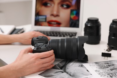 Professional photographer with digital camera at table indoors, closeup