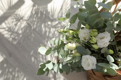 Beautiful bouquet of flowers in wicker basket on floor, above view. Space for text